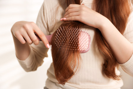 Teenage girl brushing her hair at home, closeup