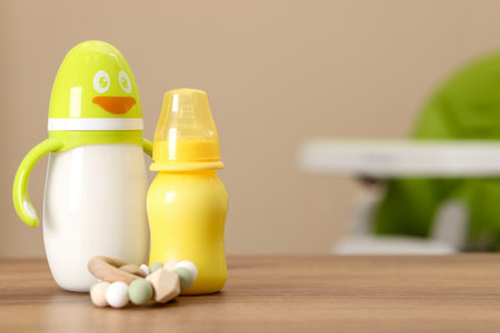 Feeding bottles with milk and toy on wooden table indoors, space for textの写真素材