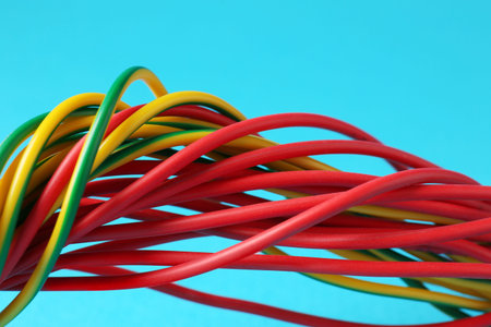 Many color electrical wires on light blue background, closeup
