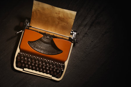 Old vintage typewriter with paper on black table, top view. Space for textの写真素材