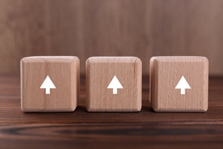 Cubes with white arrows on wooden table, closeupの写真素材