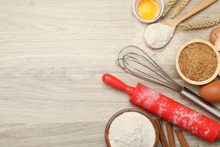 Rolling pin and different ingredients on light wooden table, flat lay. Space for text
