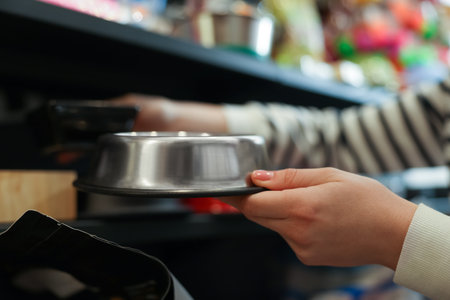 Woman choosing feeding bowl in pet shop, closeupの写真素材