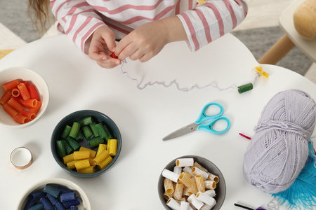 Little girl making craft at white table indoors, top view. Child creativity and handmade handicraftの写真素材