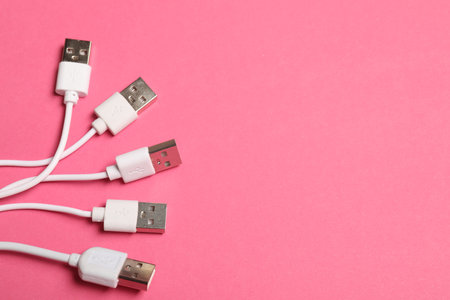 USB charge cables on pink background, flat lay. Space for textの写真素材