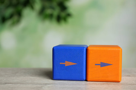 Blue and orange cubes with arrows on wooden tableの写真素材