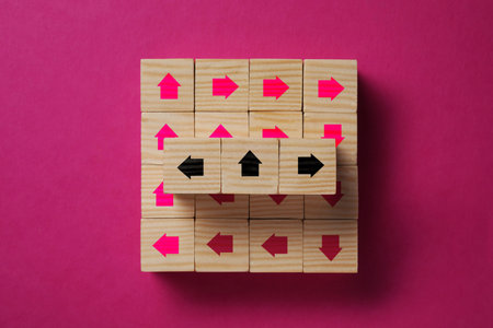 Wooden cubes with arrows on dark pink background, top viewの写真素材
