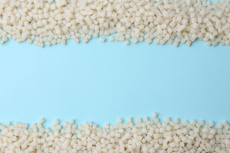 Pile of plastic granules on light blue background, top view. Space for text