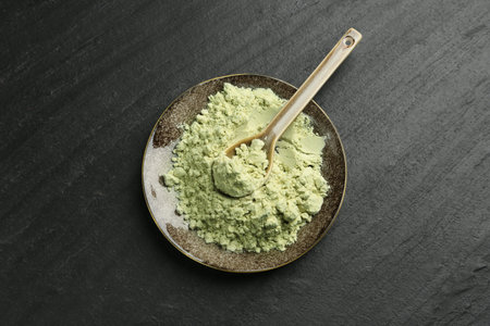 Plate with dry wasabi powder and spoon on dark textured table, top viewの写真素材