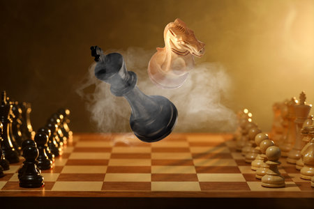 Chess game. White knight and black king in air over chessboardの写真素材