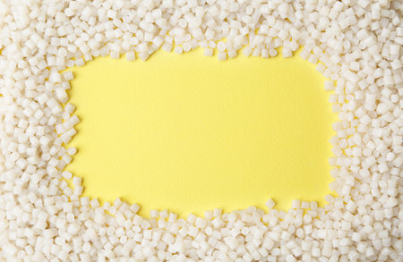 Frame of plastic granules on yellow background, top view. Space for textの写真素材