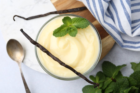 Tasty vanilla pudding, mint and pods on light grey table, flat layの写真素材