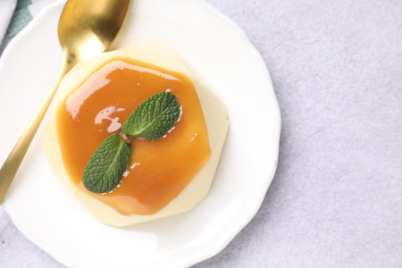 Delicious pudding with caramel sauce and mint served on light table, top viewの写真素材