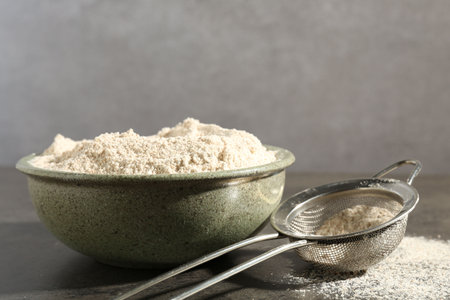 Brown rice flour and sieve on grey table, closeup. Space for textの写真素材