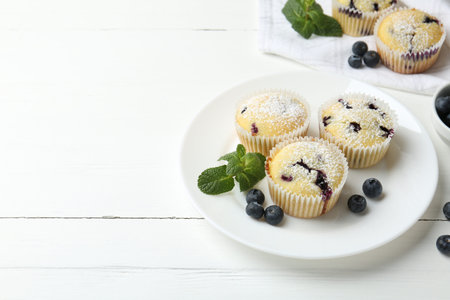 Delicious muffins with blueberries, powdered sugar and mint on white wooden table. Space for textの写真素材