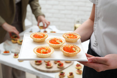 Woman holding board with tasty canapes indoors, closeup