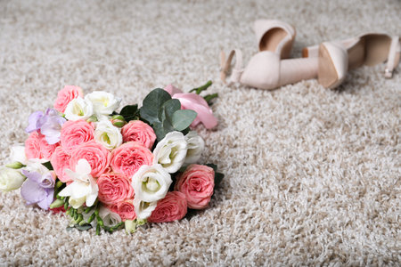 Wedding bouquet of beautiful flowers and bridal shoes on beige carpet, selective focusの写真素材