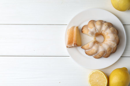 Delicious lemon cake with glaze and citrus fruits on white wooden table, flat lay. Space for textの写真素材