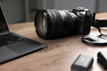 Professional photo camera and laptop on wooden desk indoorsの写真素材