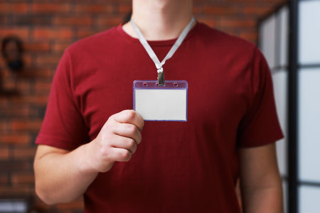 Man with blank badge in office, closeup