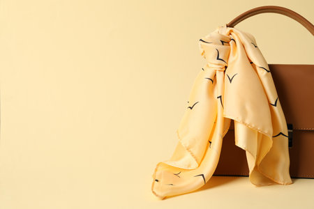 Leather bag with handkerchief on beige background, closeup. Space for textの写真素材