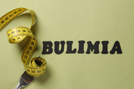 Word Bulimia, measuring tape and fork on olive background, top viewの写真素材
