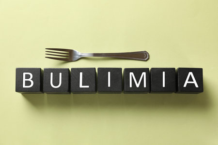 Word Bulimia and fork on olive background, top viewの写真素材
