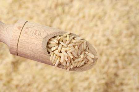 Brown rice in wooden scoop over pile of grains, top viewの写真素材