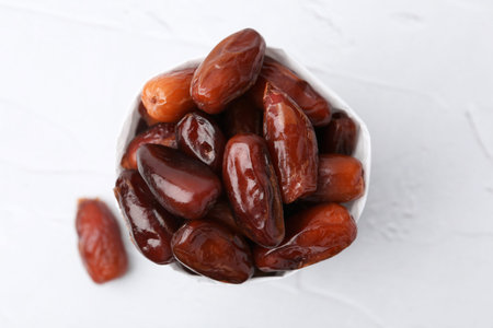 Tasty sweet dried dates in paper bag on white table, top viewの写真素材