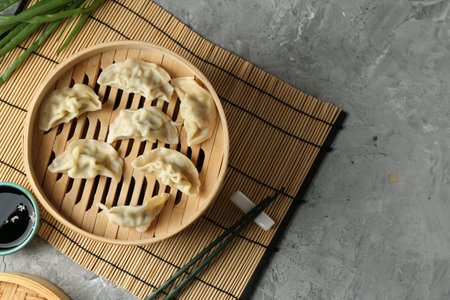 Tasty boiled gyoza (dumplings) in bamboo steamer on light grey table, flat lay. Space for textの写真素材