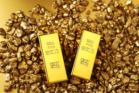 Gold nuggets and bars on shiny background, top view