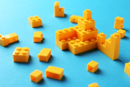 Constructor toy. Many yellow building blocks on light blue background, closeupの写真素材
