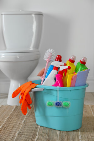 Bucket with different cleaning supplies on floor in bathroomの写真素材