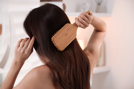 Woman brushing her beautiful hair at homeの写真素材