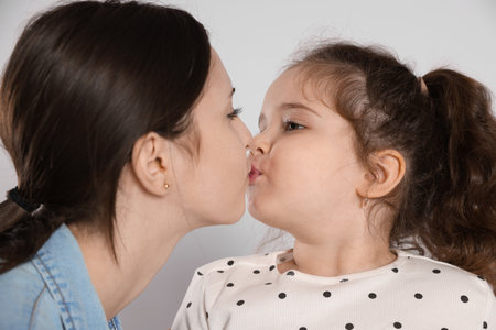 Cute little girl kissing her sister on white backgroundの写真素材