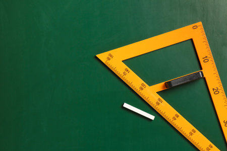 Triangle ruler and chalk on green chalkboard, top view. Space for textの写真素材