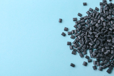 Pile of black plastic granules on light blue background, top view. Space for textの写真素材