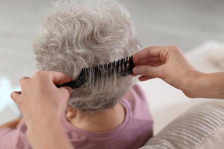 Woman brushing senior lady with comb indoors, closeupの写真素材