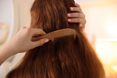 Teenage girl brushing her hair with comb at home, closeup