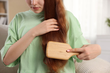 Teenage girl brushing her hair at home, closeup