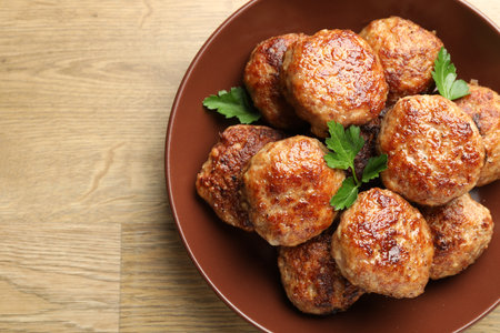 Delicious patties with parsley on wooden table, top view. Space for textの写真素材
