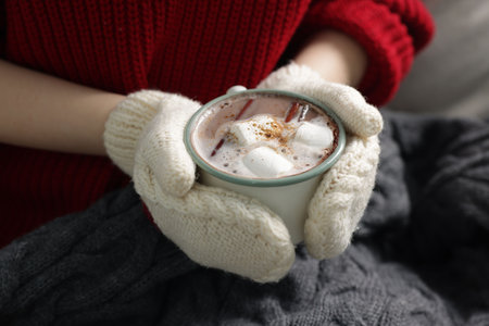 Woman holding mug of hot chocolate with marshmallows and cinnamon, closeup
