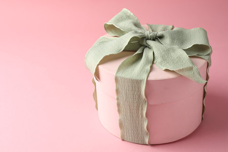 Gift box with light green bow on pink background, closeup. Space for textの写真素材