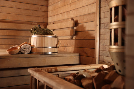 Bucket, whisk, ladle and towels on wooden bench in saunaの写真素材