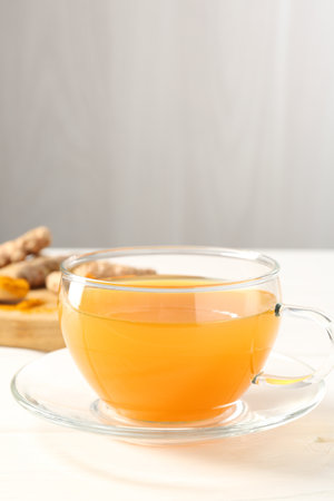 Aromatic turmeric tea in glass cup on white table, closeupの写真素材