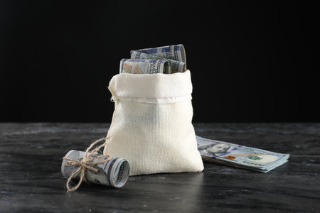 Burlap sack with dollar banknotes on gray tableの写真素材