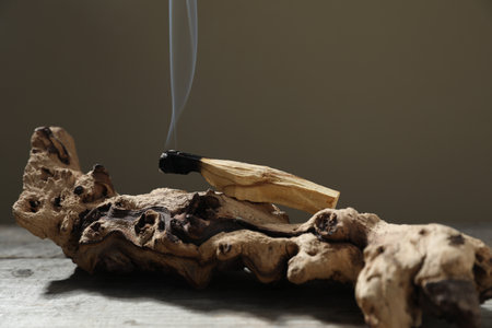Smoldering palo santo stick and snag on wooden table against grey background, closeupの写真素材
