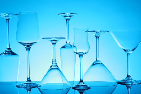 Many empty clean glasses on mirror surface against blue backgroundの写真素材