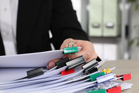 Woman holding sheets of paper with metal binder clips at table, closeupの写真素材