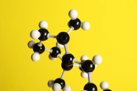 Molecule of retinol (vitamin A) on yellow background, closeup. Chemical modelの写真素材